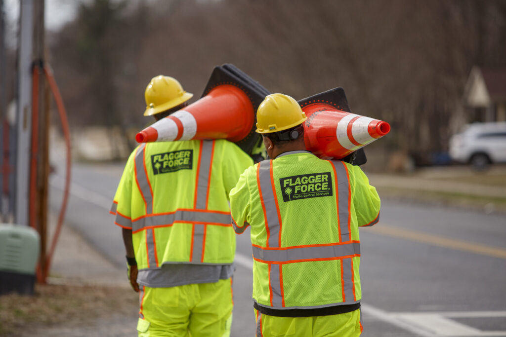 Employees working together carrying cones while setting up a work zone