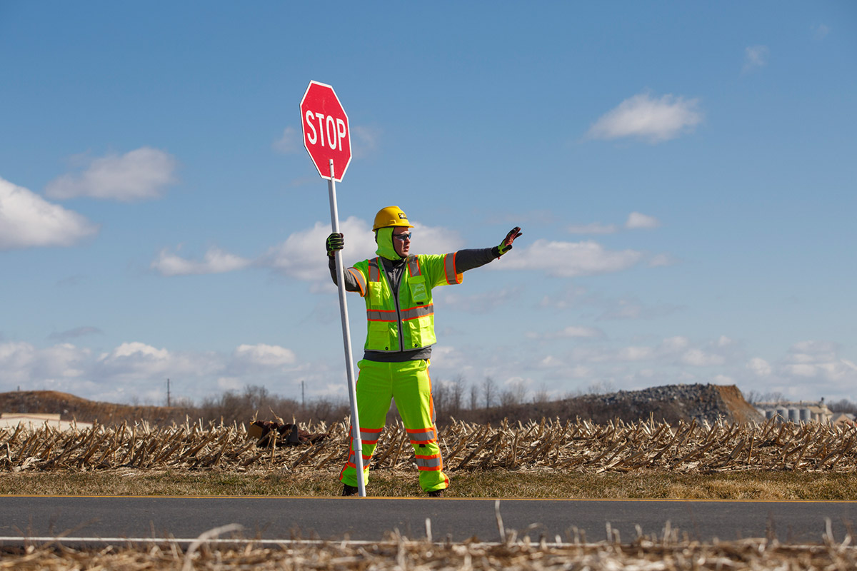 flagger-force-employee-holding-hand-out-to-stop-traffic-on-country-road